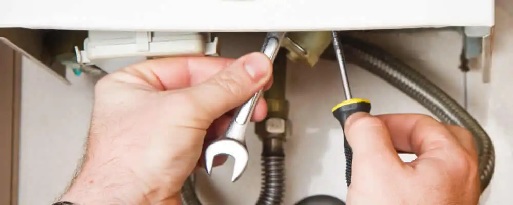 Boiler repair technician tightening pipe fittings and connections in San Mateo, CA