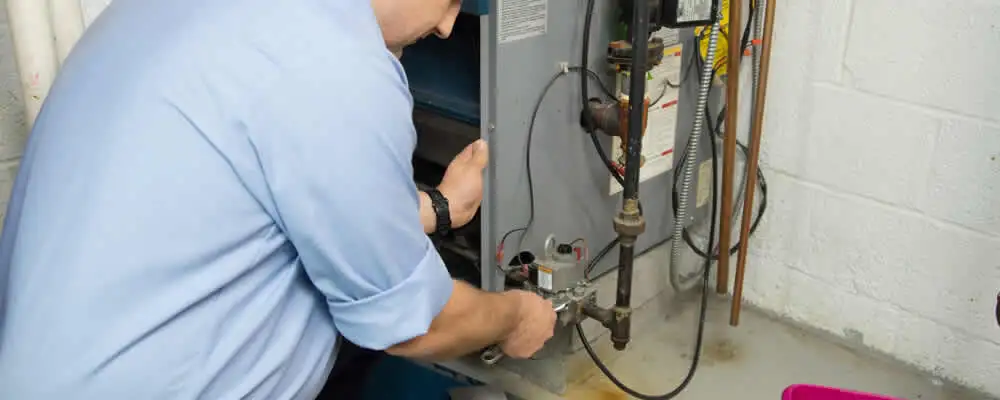 Furnace repair technician inspecting and servicing a home heating system in San Mateo, CA