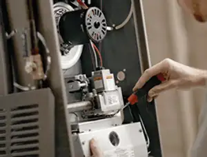 Furnace repair technician inspecting internal components and wiring in San Mateo, CA