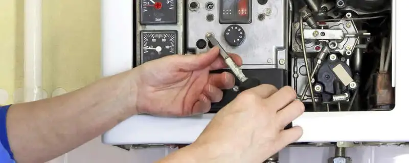 Heating repair technician adjusting boiler controls and components in San Mateo, CA