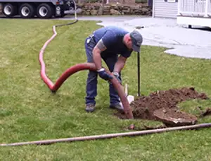 Septic pumping technician servicing a residential septic tank with a vacuum hose in San Mateo, CA