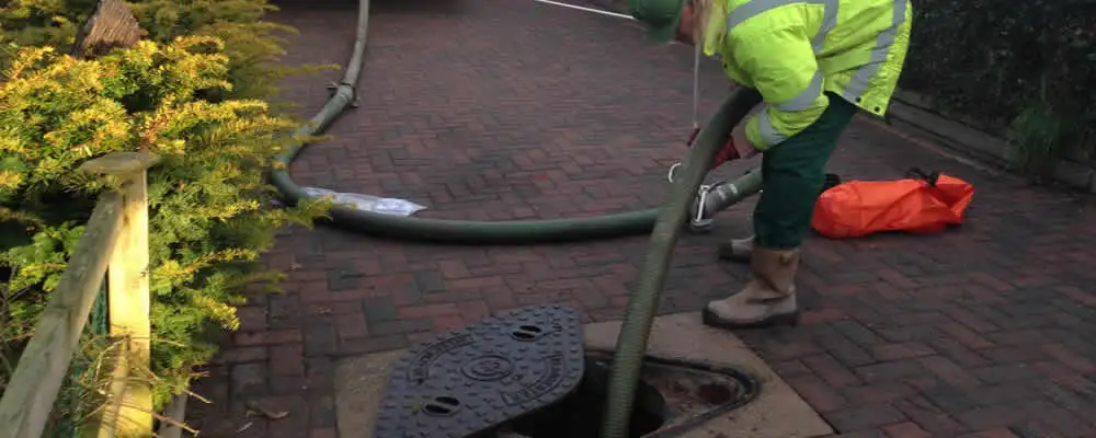 Septic tank cleaning technician servicing a septic tank with a vacuum hose in San Mateo, CA