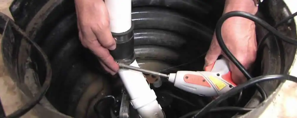 Sump pump installation technician connecting PVC discharge piping in San Mateo, CA